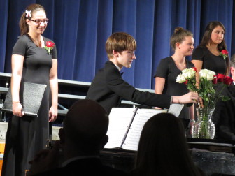 Senior, Chris Forseberg placing his rose in the vase on the piano. credit jason trabish