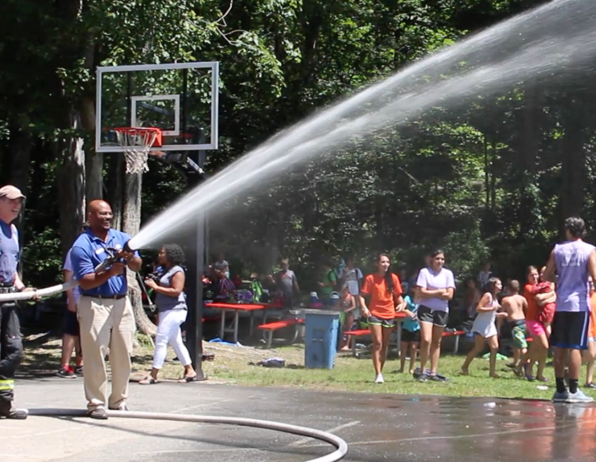 Bobby Walker, Exec Director of Greenwich Boys & Girls Club has a turn with the hose at Camp Simmons