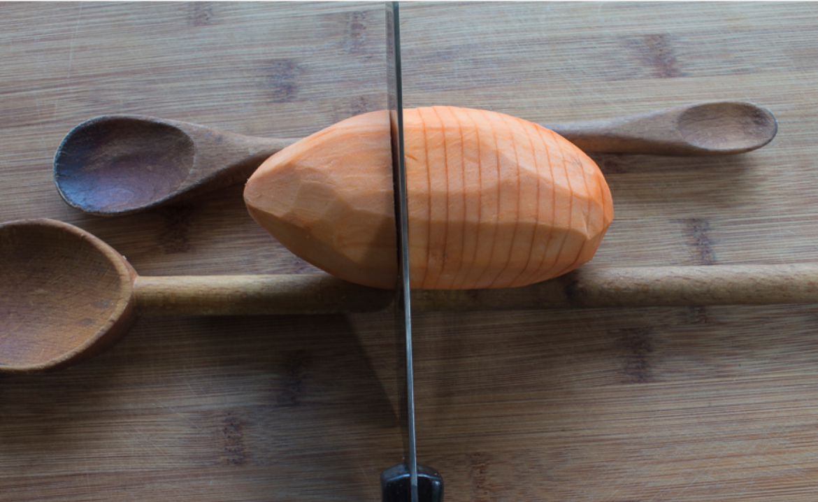 Place potatoes with wooden spoons (or chopsticks) on each side as a guide – cut in 1/4 ” intervals, not all the way through for a perfect “fan” shape