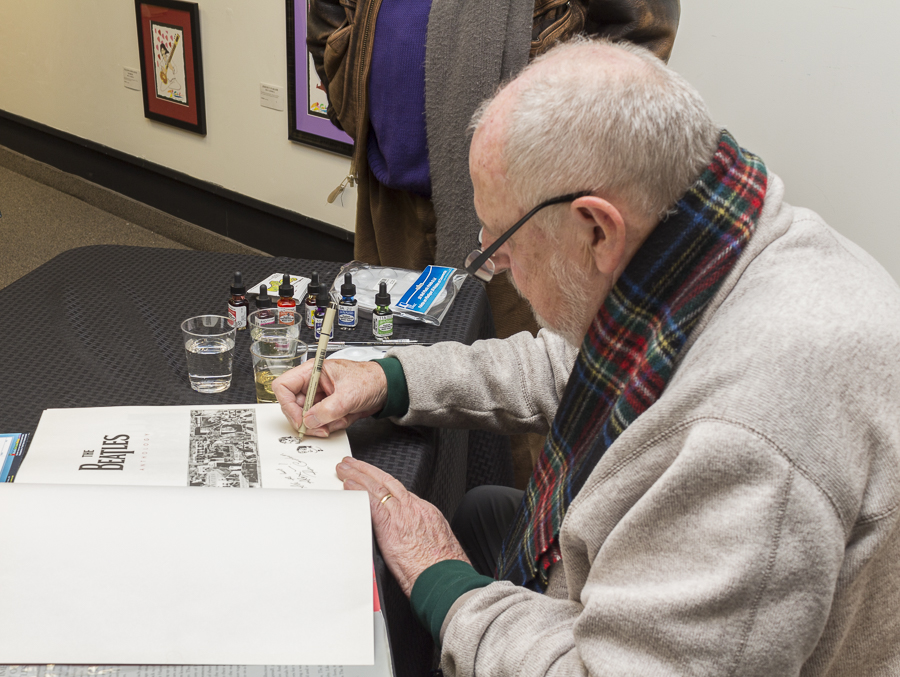 The artist personalizing a Beatles book with his colorful signature and a whimsical drawing. Credit: Karen Sheer 