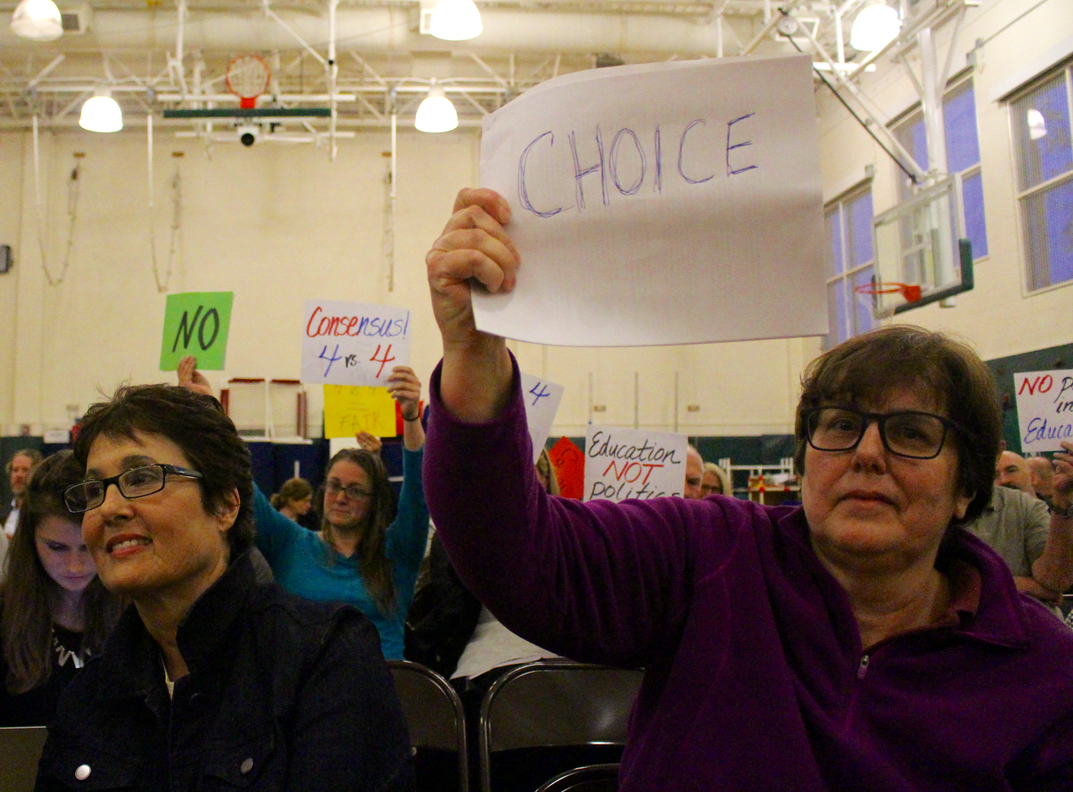 Karen Fassuliotis at a BOE meeting with a sign indicating her support BOE Charter Change. Credit Julia Moch