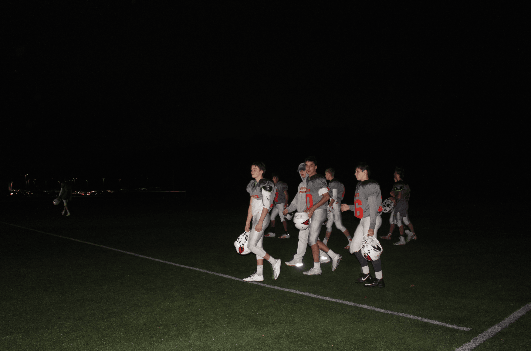 Camera flash illuminates field as JV football players walk back toward GHS following game on field 7 against Ridgefield. Nov 6, 2017 Photo: Leslie Yager
