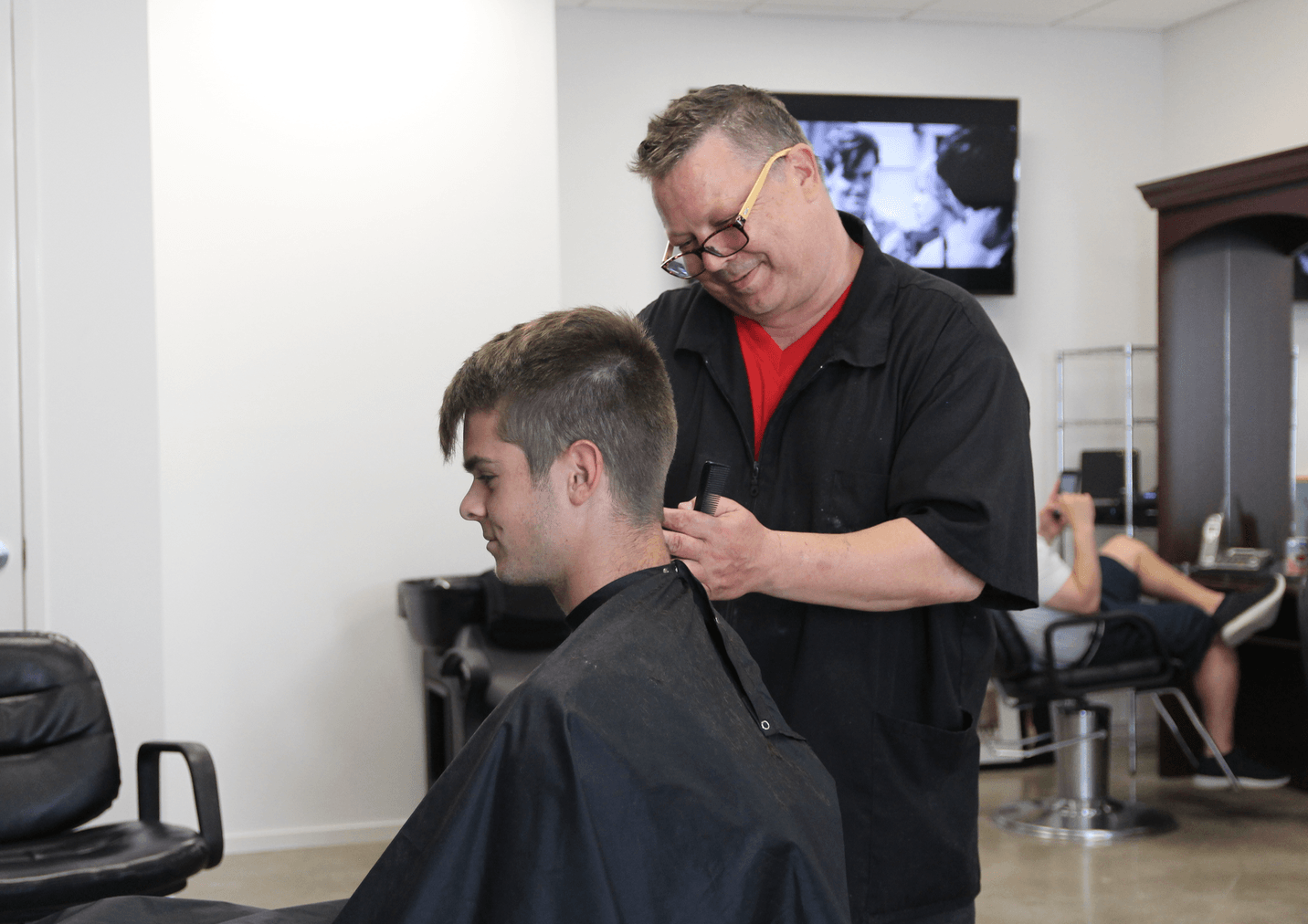 Taylor Ford, who had just come home from college, was having his hair cut by Glenn Podbielski at Avenue Barber. May 25, 2018 Photo: Leslie Yager