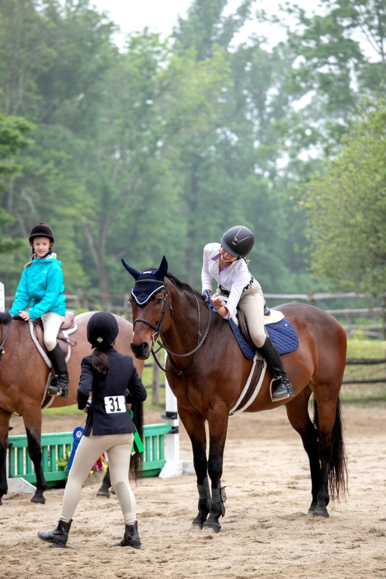 A rider congratulates her horse after winning first place in their class.