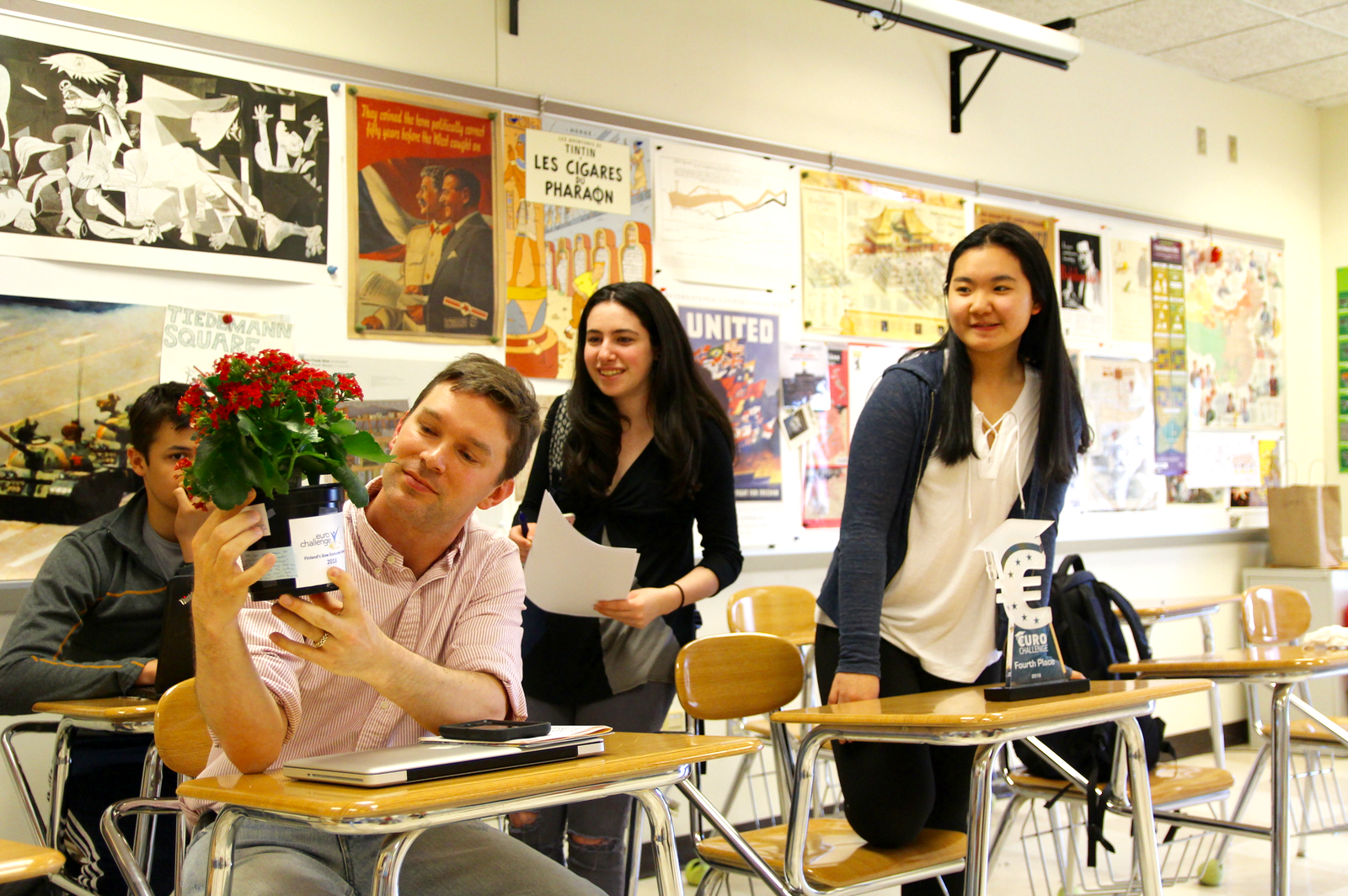 Julia Blank and Melissa Woo look on as Mr. Tiedeman reads the personal notes from this students attached to a plant they gave him. May 1, 2018 Photo: Leslie Yager