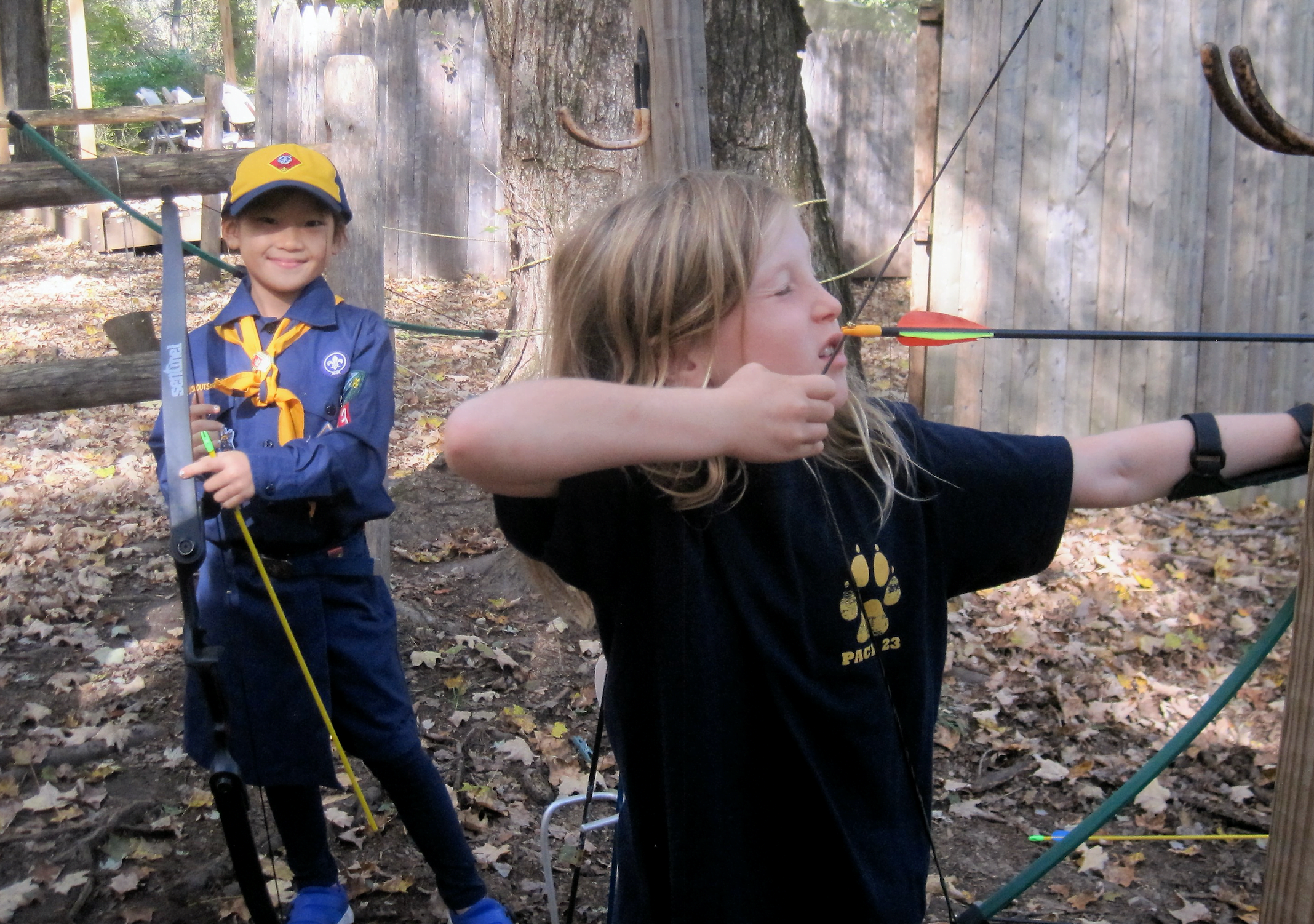 Cub Scout Coco Lee watches Charlotte DiPreta take aim on the archery range at Greenwich Scouting's Fall Festival at Seton Scout Reservation.