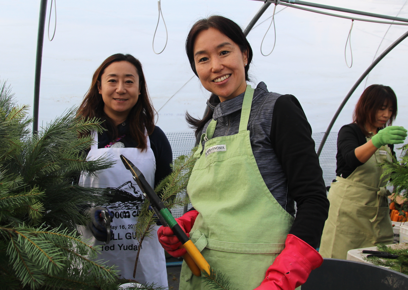 Yoshiko Suzuki and Naoko Samejima assemble baskets of greenery in one of the heated greenhouses provided by Sam Bridge. 