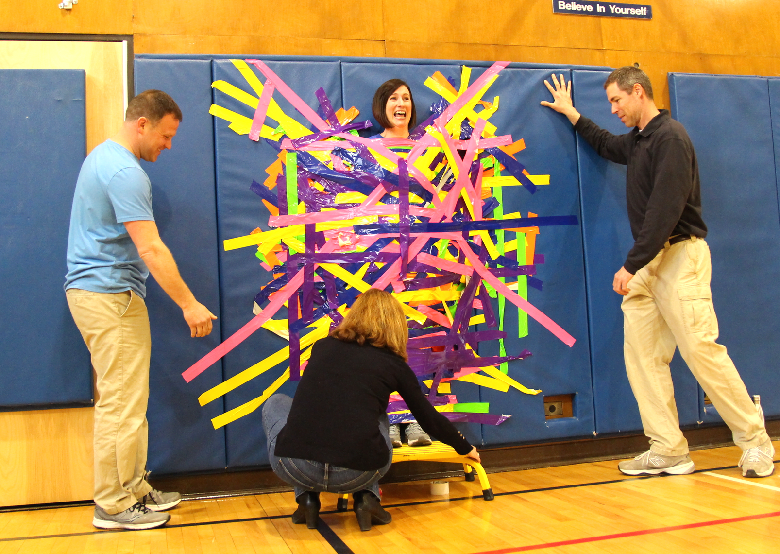 PE teachers David Bruni and Cristofer Brown with Assistant Principal Kathleen Ramirez, preparing to peel Principal Jill Flood off the wall at North Street School after a successful "pennies for patients" drive to benefit Leukemia & Lymphoma Society. March 22, 2019 Photo: Leslie Yager
