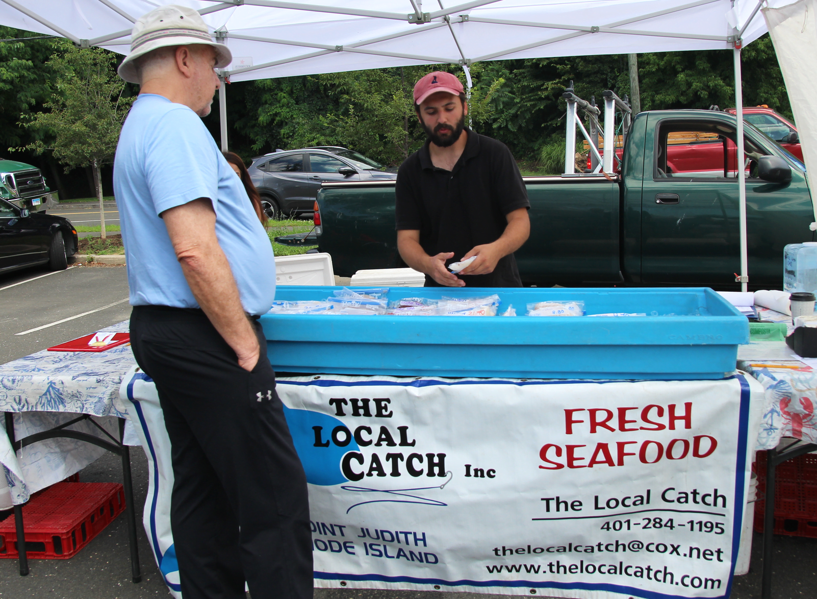 Dylan Hoy at The Local Catch explained a recipe for preparing eel to a customer at the Greenwich Farmers Market. Saturday, July 13, 2019 Photo: Leslie Yager