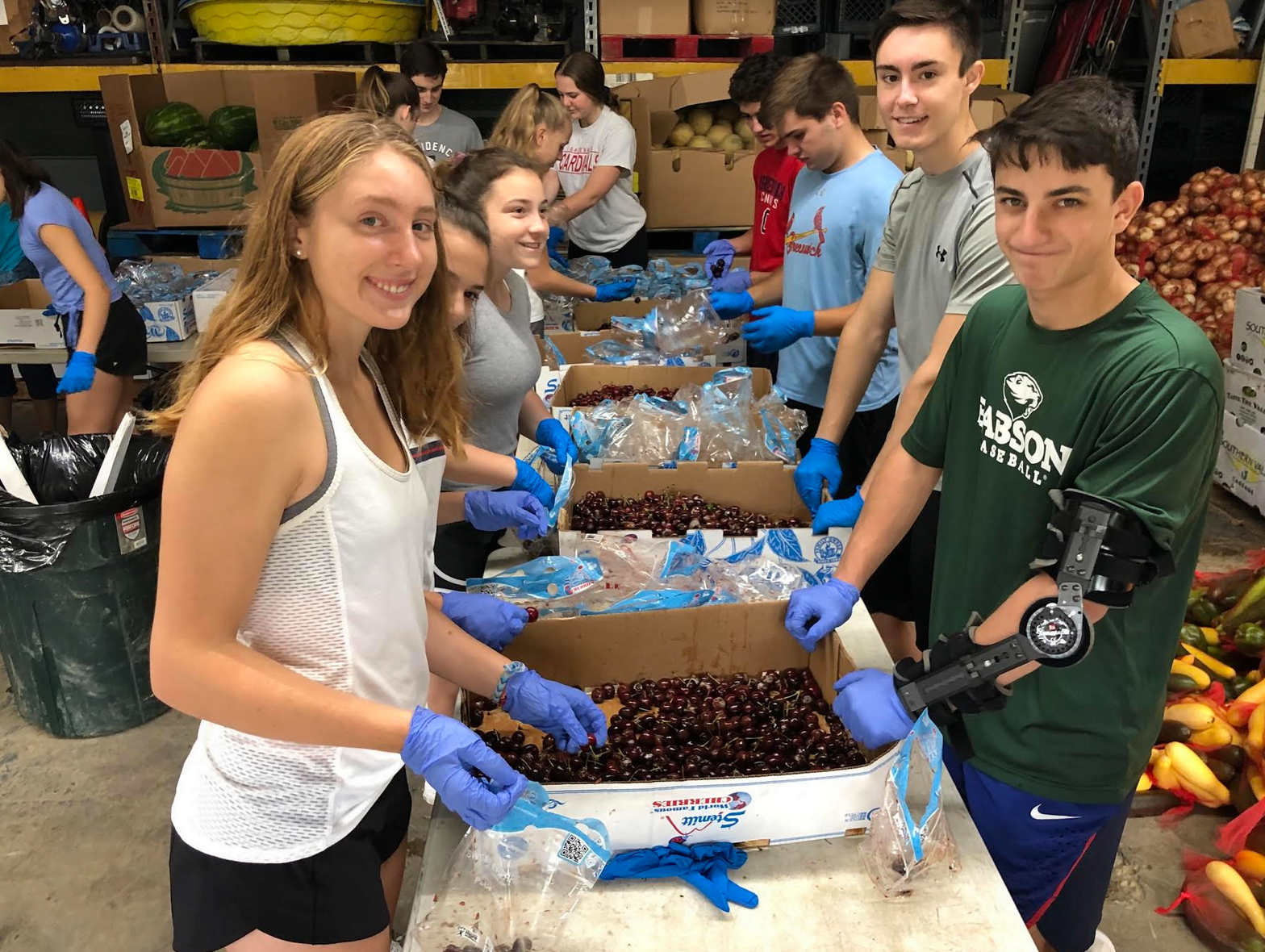 Working in the RAMP Food Pantry in Martin County, Kentucky, are Abby Shropshire, Jessica Murphy, Max Feenstra and Jake Mondschein (front four) sorting and packaging cherries to be distributed to families in need.