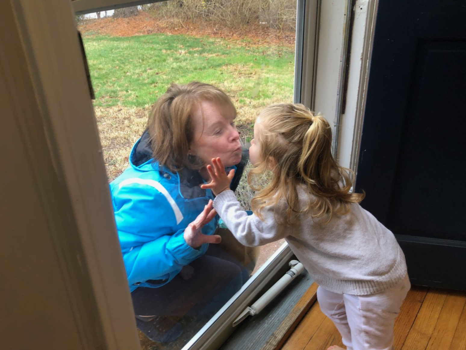 Cathy Horn of Greenwich and her granddaughter Eliza (3) share a kiss through the glass front door. contributed photo